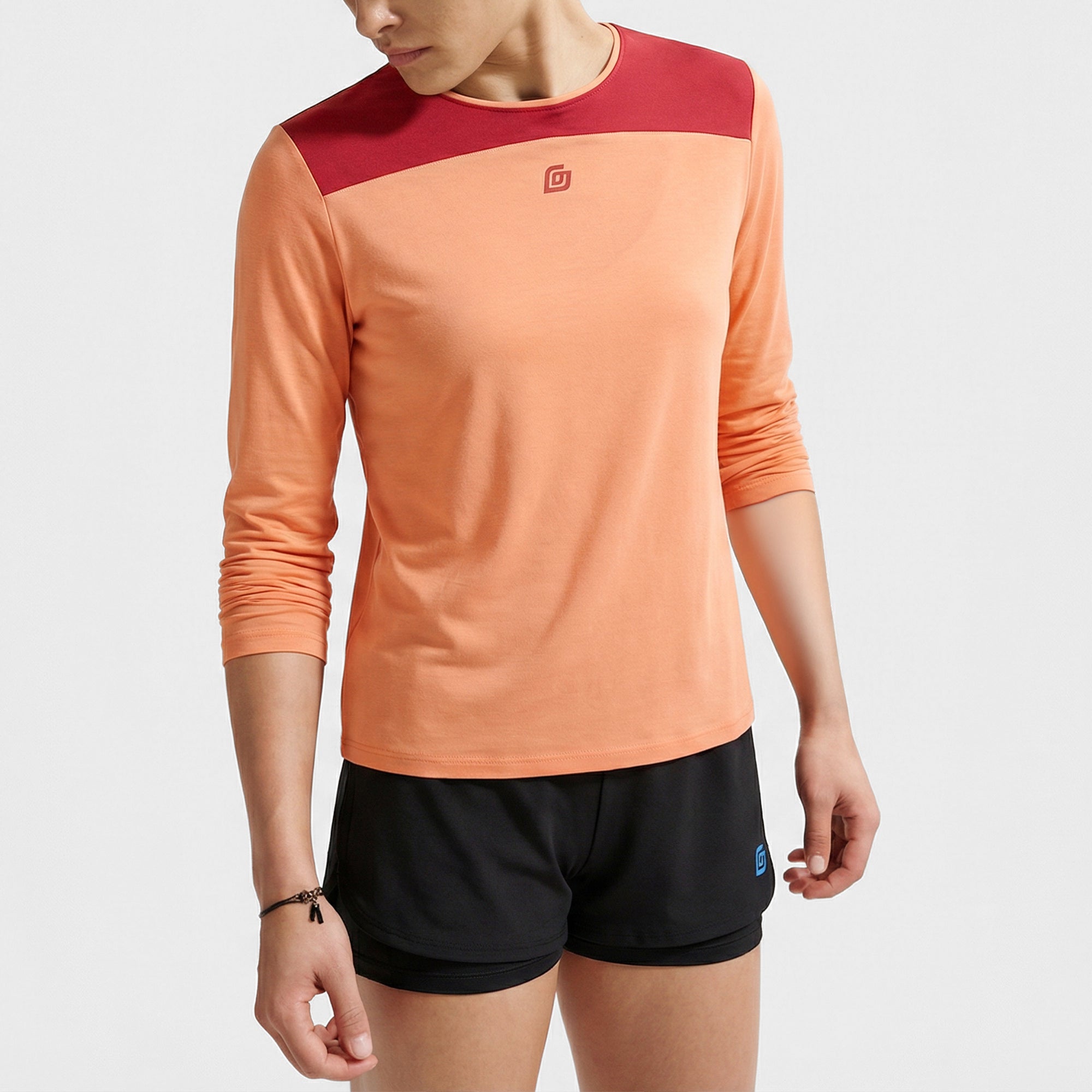 Frau trägt KiiGo Sport Longshirt aus Tencel in Pfirsich-Bordeaux kombiniert mit schwarzer 2-in-1 Short, nachhaltig produziert in Deutschland